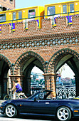 Convertible and biker. Oberbaumbrücke bridge. Berlin. Germany