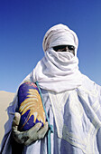 Portrait of a tuareg holding a water bottle in the Erg Admer sand dunes near Djanet Oasis. Tassili n Ajjer desert. Sahara. South Algeria
