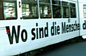 Blurred tram passin by with advertisiment Where are the men... . Innsbruck. Tyrol. Austria