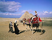 Camel riders with tourist. Pyramids of Gizeh. Egypt