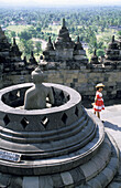 Young girl with a straw hat on top of Borobudur Buddhist Temple. Near Jogyakarta. Java Island. Indonesia