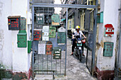 Biker on mop and mailboxes at popular housing area entrance. Guangzhou. China