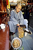 Monk preparing small sandal wood sticks to burn as incese at Jade Buddah Temple. Shanghai. China
