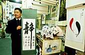 Artist selling his calligraphy work and other art in Hangzhou new pedestrians mall. Zhejiang province, China