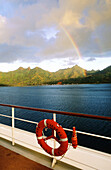 Rainbow over Huahine Island and deck of MS Paul Gauguin cruise ship. French Polynesia