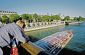 Paris-Plage Festival hold in August on the river Seine, expressway embankment closed to traffic. Sand beaches, palmes, cafes and games replace the cars.Couple looking at a tour boat on river Seine from a bridge Paris. France.
