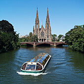 Sightseeing boat and St. Paul church in background. Strasbourg. France