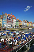 Tour boats departure pier, ancient houses and waterfront cafe terraces at Nyhavn ( New Harbor ), Copenhagen. Denmark