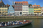 Tour boats, ancient houses and waterfront cafe terraces at Nyhavn ( New Harbor ), Copenhagen. Denmark