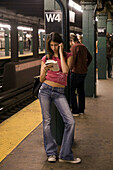 A young woman reads while waiting for her subway train in Manhattan, New York City.