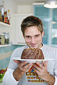 Young man holding a chocolate cake, Munich, Germany