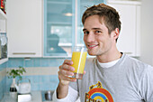 Young man drinking a glass of orange juice, Munich, Germany