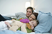 Young family lying on bed, mother and daughter sleeping, Munich, Germany