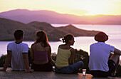 Vier junge Leute geniessen den Sonnenuntergang vom One Tree Hill auf Hamilton Island, Whitsunday Islands, Great Barrier Reef, Australien