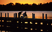 Fischer auf dem Holzsteg zum Sonnenuntergang, Lakes Entrance, Victoria, Australien