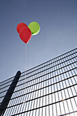 Three helium balloons hanging on fence