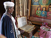 Priest showing bible and paintings at a rock hewn church in Lalibela. Ethiopia