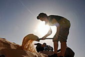 Woman shoveling sand, Adventure contest, Djebel Tembaine, Tunisia