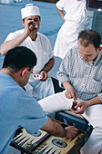  Adult, Adults, Backgammon, Board game, Board games, Color, Colour, Contemporary, Daytime, Exterior, Game, Games, Human, Leisure, Male, Man, Men, Men only, Outdoor, Outdoors, Outside, People, Person, Persons, Play, Player, Players, Playing, Plays, Seated,
