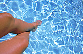 Young woman with her legs in pool