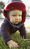 baby in jacket crawling on grass