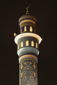 Mosque spire in Mutrah, lit up at night. Oman