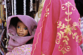 Young child is being held by women in Jodhpur bazaar. Rajasthan. India.