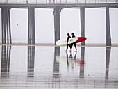 Surfers with boards in Pismo Beach, California, USA.