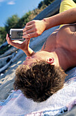 Teen lying on beach using PDA