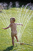 3 years old boy playing with water sprinkler