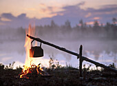 Coffee boiling over a campfire, at sunrise. Byske. Vasterbotten. Sweden.