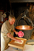 alpine cowboy making cheese in front of copper kettle, Ranggenalm, Kaiser range, Tyrol, Austria