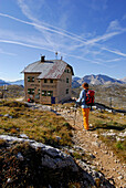 Young woman arriving at lodge Seekofel Mountain Lodge, Alta Via delle Dolomiti No. 1, Parco Naturale Fanes-Sennes, Dolomites, South Tyrol, Alta Badia, Italy