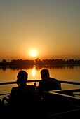 Nilkreuzfahrt, Pärchen auf dem Oberdeck, Sonnenuntergang über den Palmen am Westufer, Nil Abschnitt Luxor-Dendera, Ägypten, Afrika