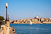 Menschen auf der Uferpromenade von Sliema mit Blick auf die Stadt Valletta, Malta, Europa