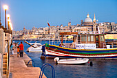 Menschen am Abend auf der Uferpromenade von Sliema mit Blick auf Valletta, Malta, Europa