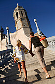 Couple walking upstairs to a church, Sitges, Catalonia, Spain