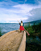 Uru indian woman and totora reeds boat. Titicaca Lake. Peru