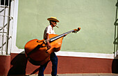 Bass Player carrying his instrument in a Street of Trinidad de Cuba. Cuba
