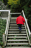 Man climbing outdoor wooden staircase, stairwell or steps.