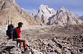 Trekker on Baltoro glacier, unnamed Trango spire behind. Karakoram mountains, Pakistan