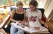 Teenagers reading. Boyfriend and girlfriend in family home. Christchurch, Canterbury. New Zealand.