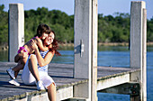Mother with daughter sitting on a dock at the beach. Florida. USA