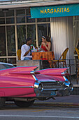 A vintage car on Collins Avenue in front of a bar, Miami Beach, Florida, USA