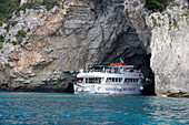 Ausflugsschiff mit Touristen fährt in eine Höhle an der Westküste, Paxos, Ionische Inseln, Griechenland