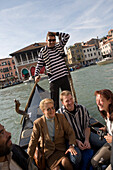 Gondolier on a gondola crossing Grand Canal with passengers, Venice, Veneto, Italy