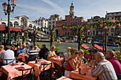 People sitting on the terrace of Cafe Saraceno near Rialto Bridge, Venice, Veneto, Italy