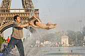 Vater und Sohn spielen am Springbrunnen vor dem Eiffelturm, Paris, Frankreich, Europa