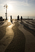 Menschen auf der Strandpromenade bei Sonnenuntergang, Lazise, Gardasee, Italien, Europa