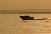 Small motorboat on lake Garda at sunset, Italy, Europe